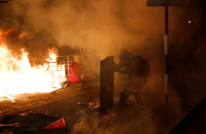 A protester takes cover during a standoff with riot police at the Chinese University of Hong Kong