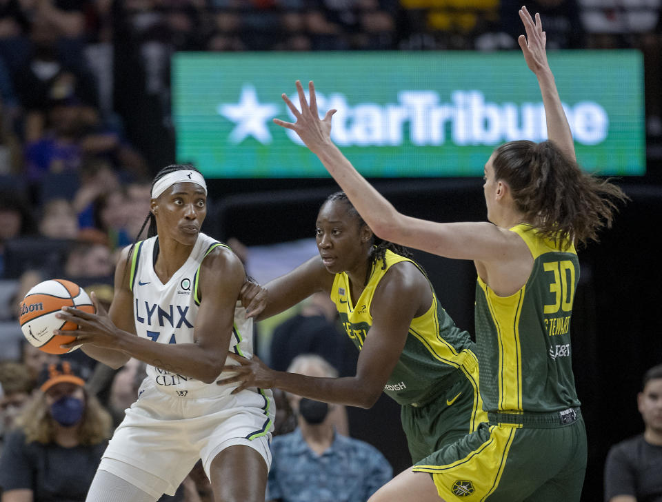 Minnesota Lynx center Sylvia Fowles (34) is guarded by Seattle Storm's Tina Charles, center, and Breanna Stewart (30) during the first quarter of a WNBA basketball game Friday, Aug. 12, 2022, in Minneapolis. (Elizabeth Flores/Star Tribune via AP)