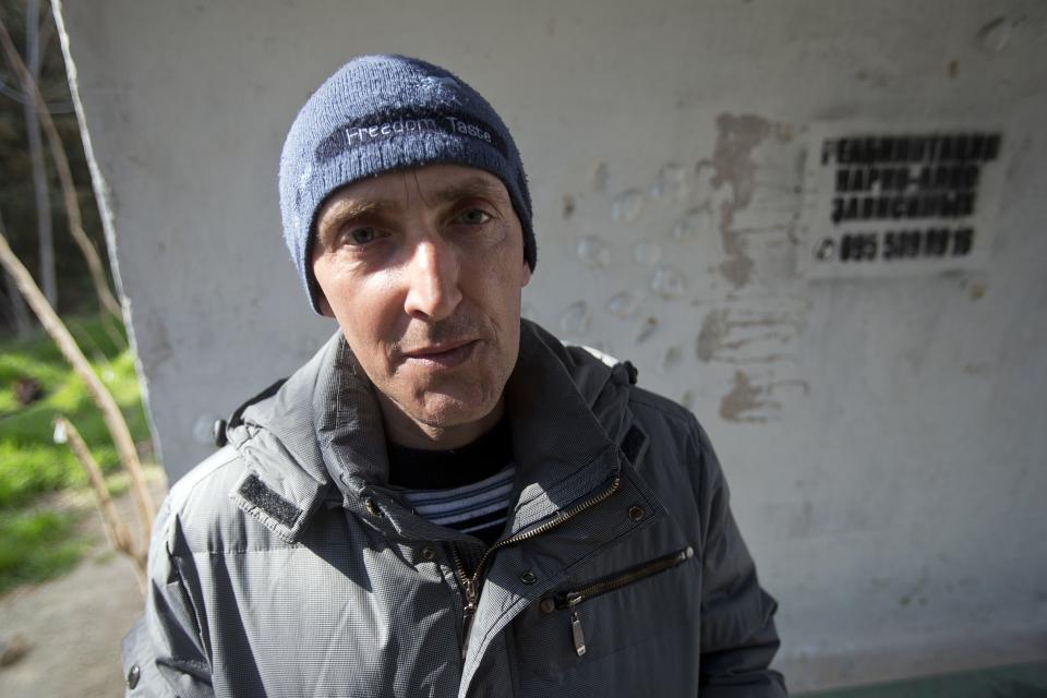 In this photo taken Tuesday, April 1, 2014, Boris Dashkovsky, a patient of treatment for drug addiction, poses at a bus stop with an advert reading "Rehabilitation of drug and alcohol addicts" in Sevastopol, Crimea. Across the Black Sea peninsula, some 800 heroin addicts and other needle-drug users take part in methadone programs, seen as an important part of efforts to curb HIV infections by taking the patients away from hypodermic needles that can spread the AIDS-causing virus. After Russia's annexation of Crimea methadone was banned. The ban could undermine years of efforts to reduce the spread of AIDS in Crimea. (AP Photo/Pavel Golovkin)