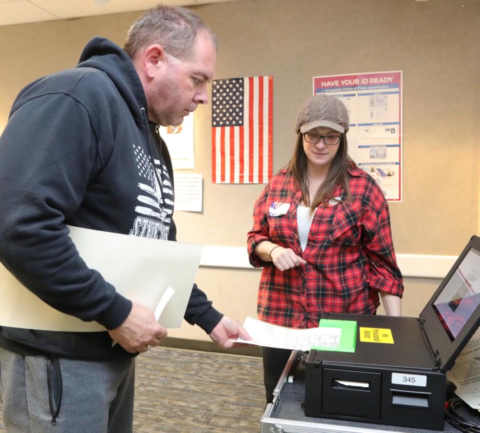 Paul Dorsey is assisted by poll worker Rachel Radcliffe after casting his ballot at the Nordonia Hills City Branch Library polling station on Tuesday.