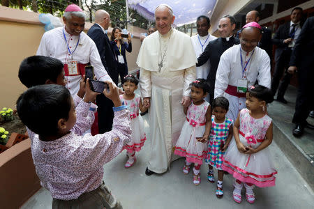 Children take photos of Pope Francis as he leaves after meeting with sick people and staff of the Mother Teresa House in the Dhaka's Tejgaon neighborhood, Bangladesh, December 2, 2017. REUTERS/Andrew Medichini/Pool