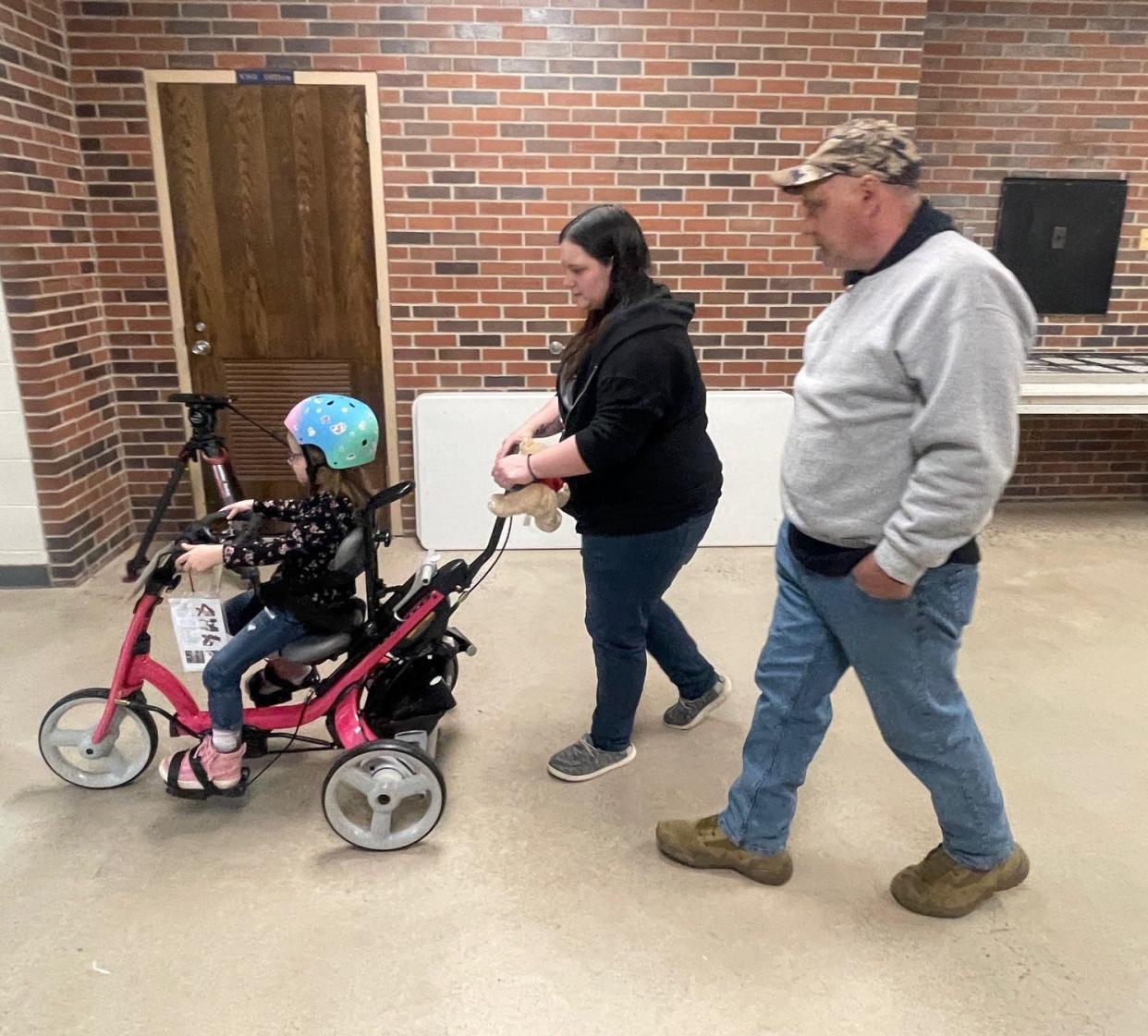 Taylor Ogline pedals her bike down the hallway at the Greater Johnstown Career and Technology Center. Taylor's mom, Kaylee Ogline, and grandfather, Joseph Schuck, of Hollsopple, are walking behind her.