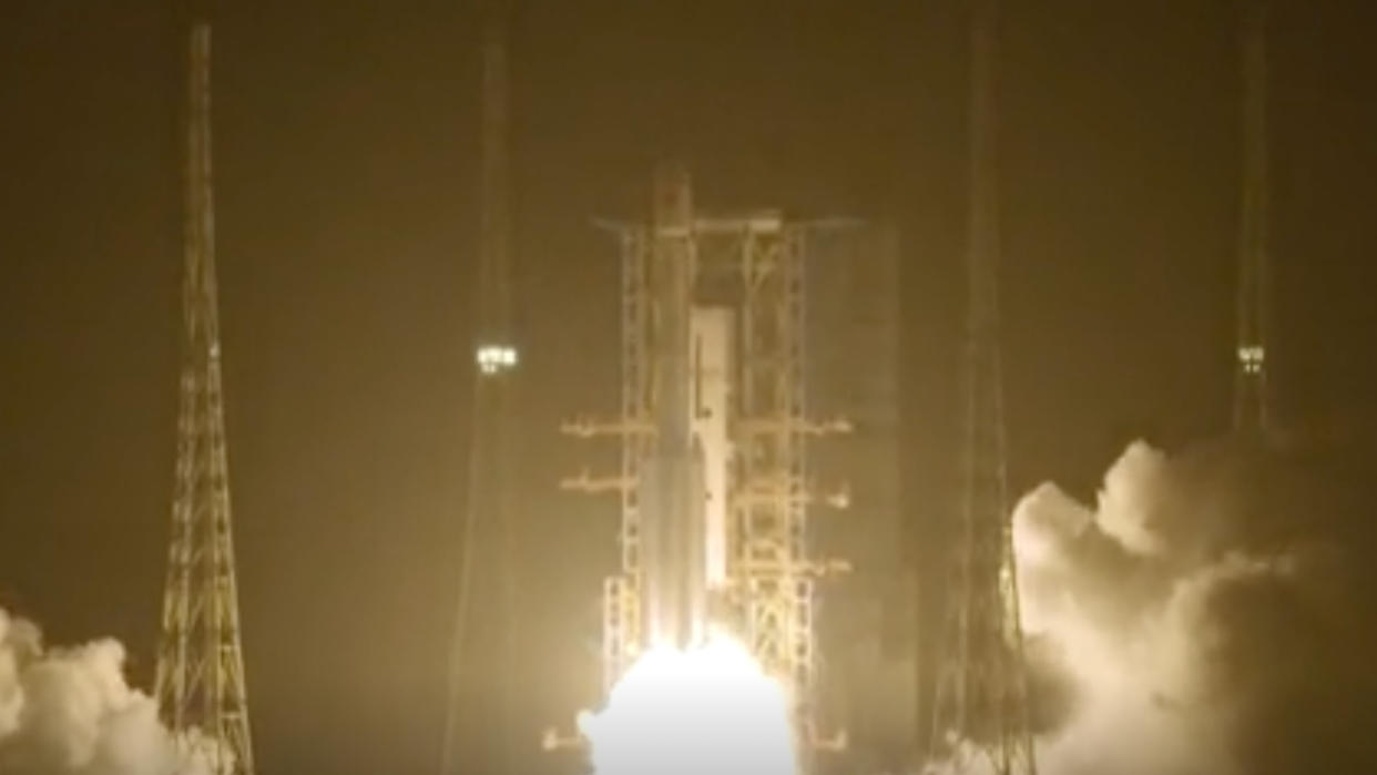  A white rocket launches into a night sky. 