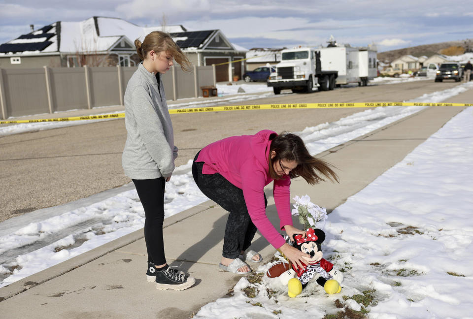 Alecia Jones, right, with her daughter Brooklyn, 13, places a Minnie Mouse stuffed animal by police tape near a home where eight members of a family were killed in Enoch, Utah, on Thursday, Jan. 5, 2023. Brooklyn was friends with one of the victims. A Utah man fatally shot his five children, his mother-in-law and his wife, then killed himself two weeks after the woman had filed for divorce, according to authorities and public records. (Laura Seitz/The Deseret News via AP)