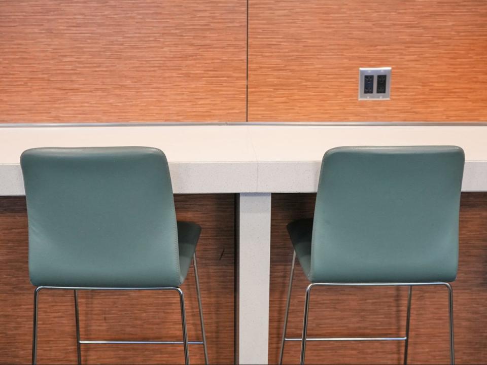 Two blue chairs in front of a white table with a wooden wall and outlet in front of them