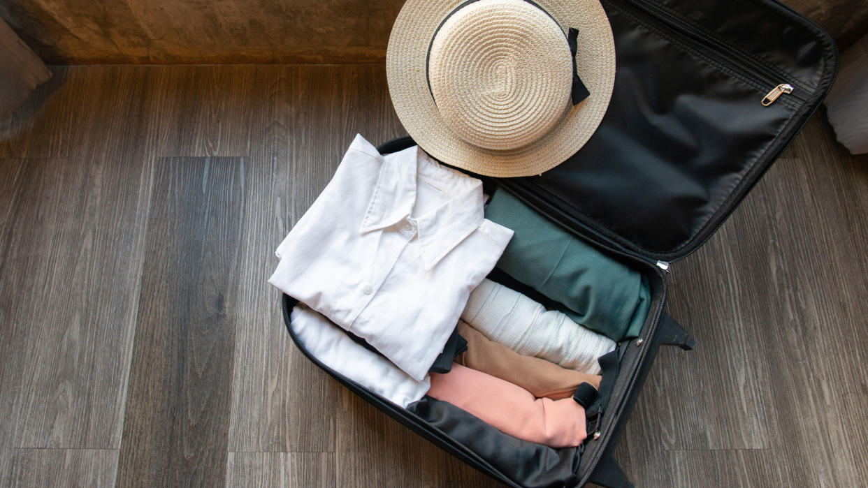  folded shirts in suitcase with summer hat 