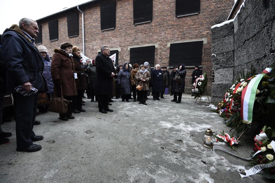 Polish President Bronislaw Komorowski (C), Piotr Cywinski (C-R, hidden), director of the Auschwitz-Birkenau museum and Auschwitz survivors lay down a wreath at the death wall of the former Auschwitz concentration camp on January 27, 2015 at the camp's memorial site in Oswiecim, Poland. Seventy years after the liberation of Auschwitz, ageing survivors and dignitaries gather at the site synonymous with the Holocaust to honour victims and sound the alarm over a fresh wave of anti-Semitism. 