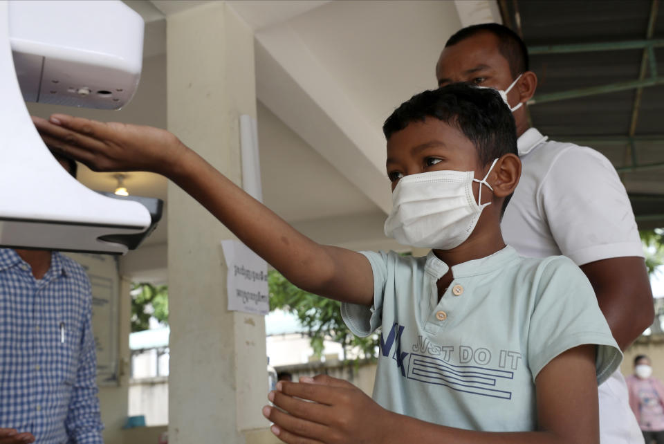 A young boy, left, disinfects his hands before receiving a shot of the Sinovac's COVID-19 vaccine at Samrong Krom health center outside Phnom Penh, Cambodia, Friday, Sept. 17, 2021. Prime Minister Hun Sen announced the start of a nationwide campaign to give COVID-19 vaccinations to children between the ages of 6 and 11 so they can return to school safely after a long absence due to measures taken against the spread of the coronavirus. (AP Photo/Heng Sinith)