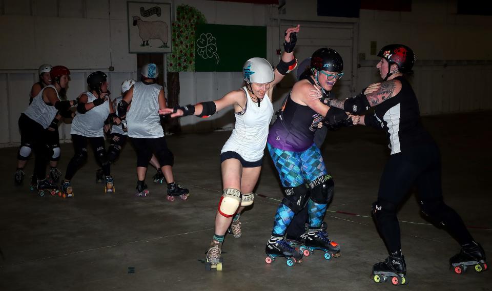 Jammer Jamie Carr (who’s known as ShredAStare on the track), left, skates around blockers, Kendal Seager (Twisted Spinster), center, and Kaylee Jankowski (Mad Medic), right, during West Sound Roller Derby practice in the Sheep Barn at the Kitsap County Fairgrounds on Monday. West Sound Roller Derby, shut down entirely since the start of the COVID-19 pandemic in 2020, returns to the fairgrounds on Saturday.