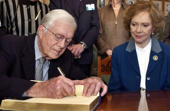 Peace Prize winner and former US president Jimmy Carter signs the guestbook in the Nobel Institute in Oslo 09 December 2002, next to his wife Rosalynn (POOL/AFP via Getty Images)