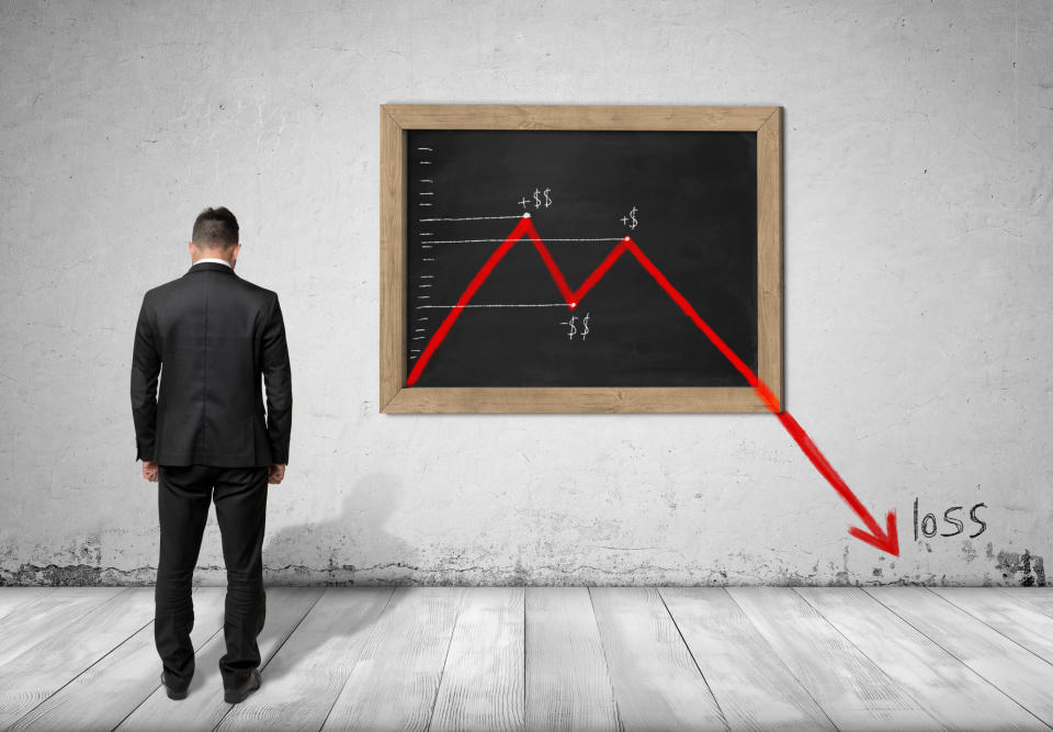Sad guy in a suit looking at a downward sloping chart.