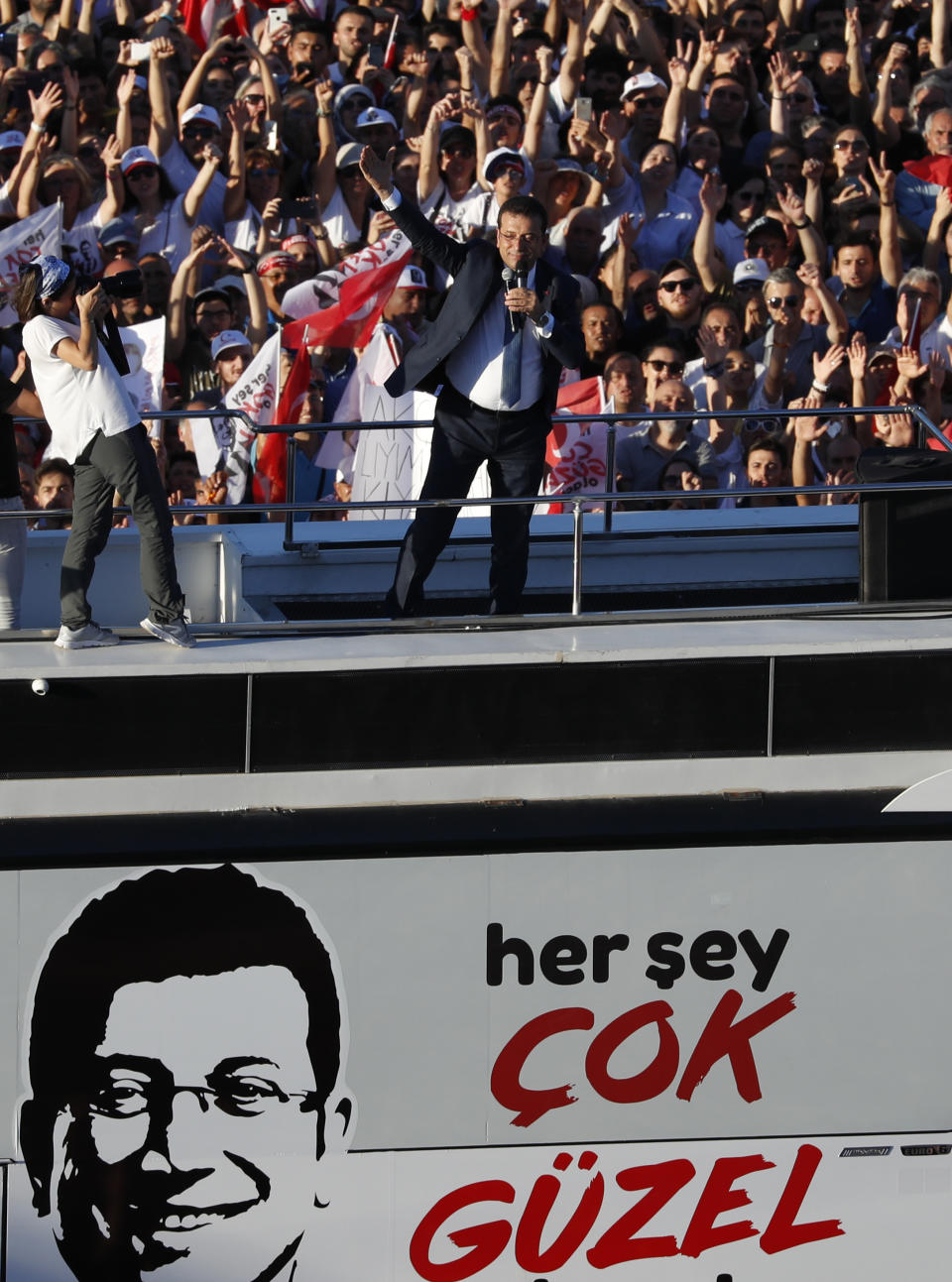 Thousands of supporters surround a bus from where Ekrem Imamoglu, centre, the new Mayor of Istanbul from Turkey's main opposition opposition Republican People's Party (CHP) makes a speech after he took over office, in Istanbul, Thursday, June 27, 2019. The sign on the bus, partially reads in Turkish: 'Everything will be great,' which was Imamoglu's main election slogan. Imamoglu is formally taking office as mayor of Istanbul four days after he won a repeat election in Turkey's largest city and commercial hub. (AP Photo/Lefteris Pitarakis)