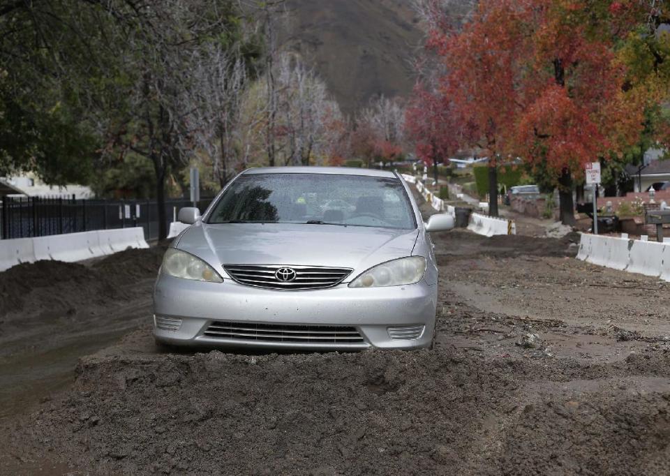 A sedan is stuck in mud and debris that flowed down slopes previously denuded by wildfires in Duarte, Calif., Friday, Dec. 16, 2016. A late fall storm has drenched California, causing some mud flows, roadway flooding and traffic snarls as it takes parting shots at the south end of the state. (AP Photo/Nick Ut)