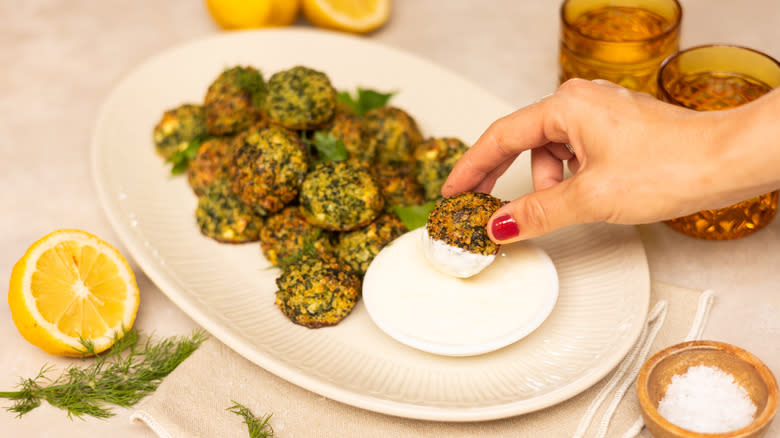 hand taking herby spinach quinoa balls on plate  