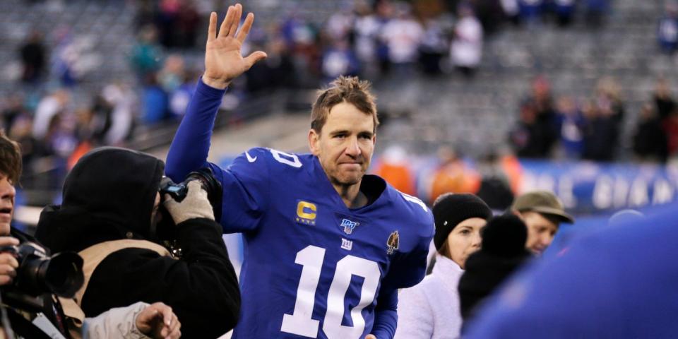 Eli Manning waves while surrounded by camermen as he runs off the field in 2019.