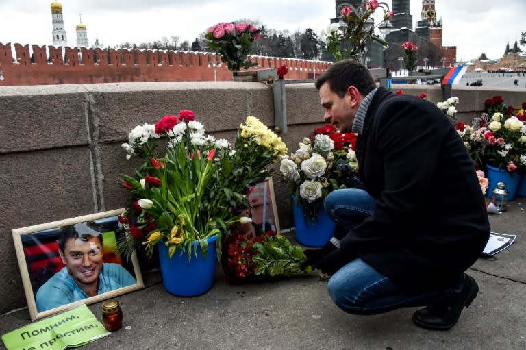 Russian opposition politician Ilya Yashin lays flowers in Moscow at the site where late opposition leader Boris Nemtsov was shot dead on a bridge near the Kremlin three years ago