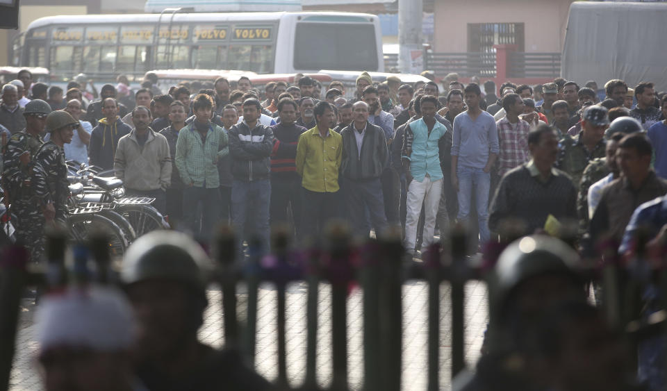 People stand behind a police barricade and watch a protest against the Citizenship Amendment Act in Nalbari, India, Friday, Dec. 20, 2019. Police banned public gatherings in parts of the Indian capital and other cities for a third day Friday and cut internet services to try to stop growing protests against a new citizenship law that have left 11 people dead and more than 4,000 others detained. (AP Photo/Anupam Nath)