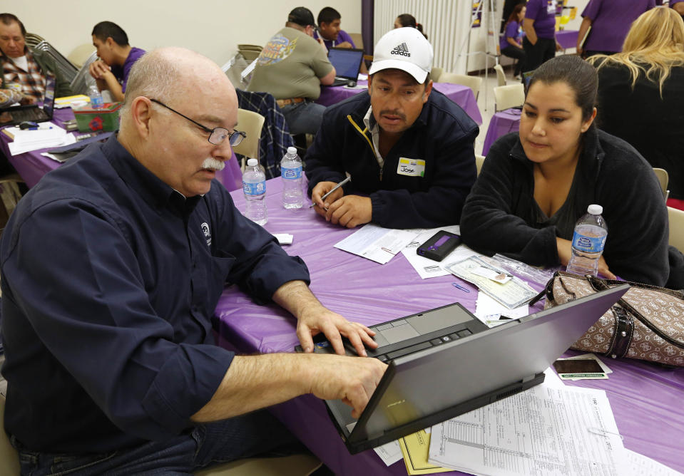 José Gomez y su esposa, Laura, reciben ayuda del agente de seguros Michael Wilson (izquierda), certificado para asesorar en el programa Cover California, para inscribirse a un plan de seguro médico en un sitio de registro hospedado por le gremio Service Employees International Union-United Healthcare Workers, el lunes 31 de marzo de 2014, en Sacramento, California. (Foto AP/Rich Pedroncelli)