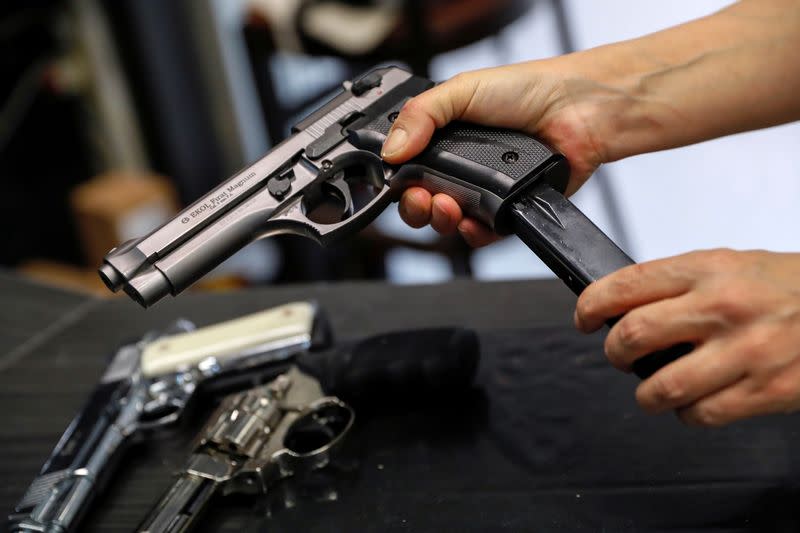 A Hungarian vendor shows an Ekol Firat Magnum gas pistol at a gun shop as people fearful of disorder from the coronavirus pandemic queue up to buy weapons for protection