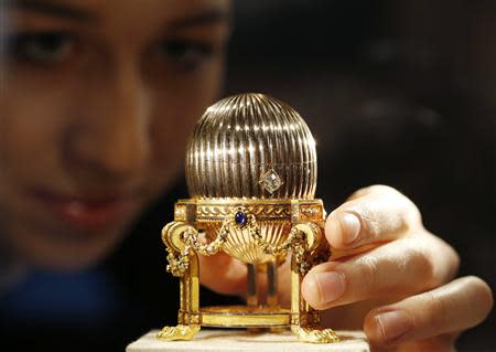 An assistant poses for a photograph with a Faberge egg during a photo-call at antique dealer Wartski, in central London April 7, 2014. REUTERS/Olivia Harris