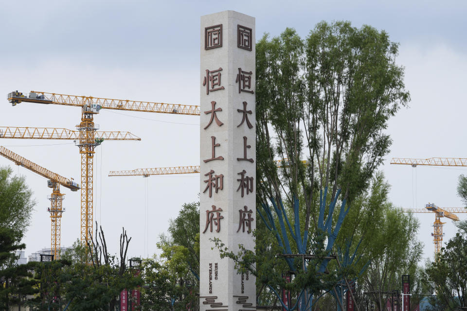 Construction cranes stand near the Evergrande's name and logo at its new housing development in Beijing, Wednesday, Sept. 15, 2021. One of China's biggest real estate developers is struggling to avoid defaulting on billions of dollars of debt, prompting concern about the broader economic impact and protests by apartment buyers about delays in completing projects. Rating agencies say Evergrande Group appears likely to be unable to repay all of the 572 billion yuan ($89 billion) it owes banks and other bondholders. That might jolt financial markets, but analysts say Beijing is likely to step in to prevent wider damage. (AP Photo/Andy Wong)