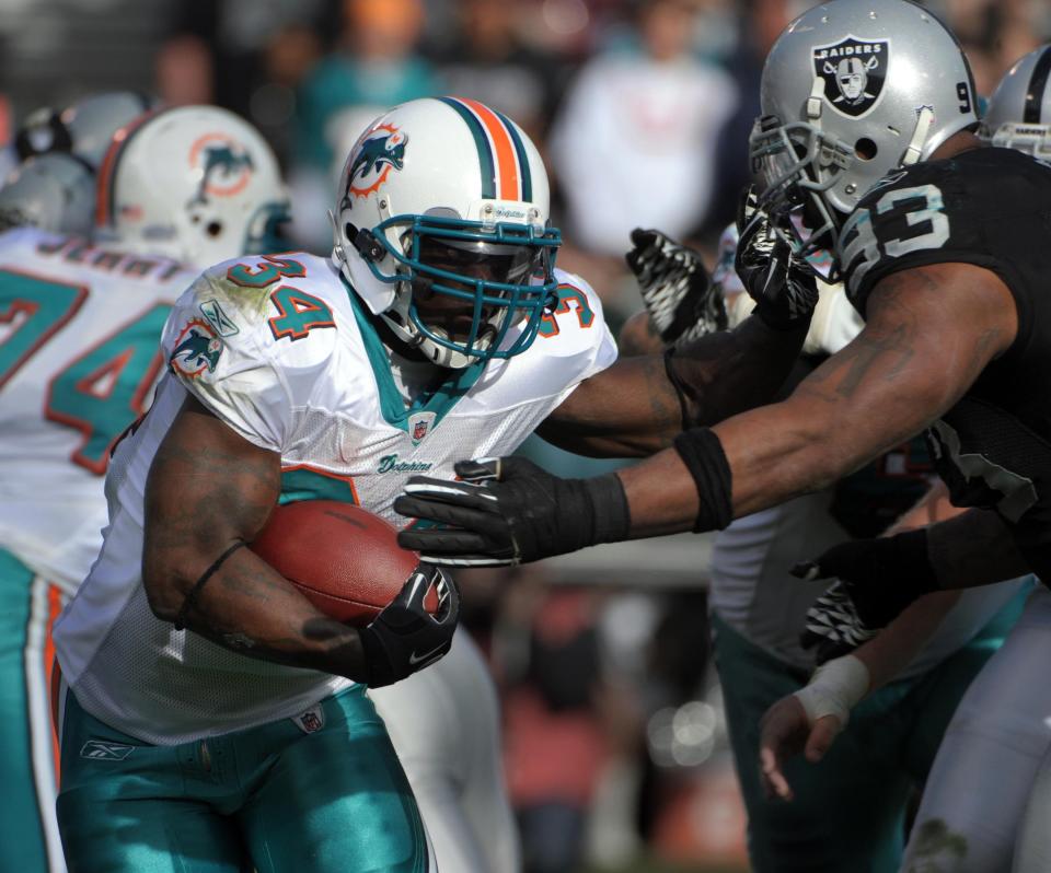 Nov 28, 2010; Oakland, CA, USA; Miami Dolphins running back Ricky Williams (34) is pursued by Oakland Raiders defensive tackle Tommy Kellly (93) at the Oakland-Alameda County Coliseum. The Dolphins defeated the Raiders 33-17. Mandatory Credit: Kirby Lee/Image of Sport-USA TODAY Sports