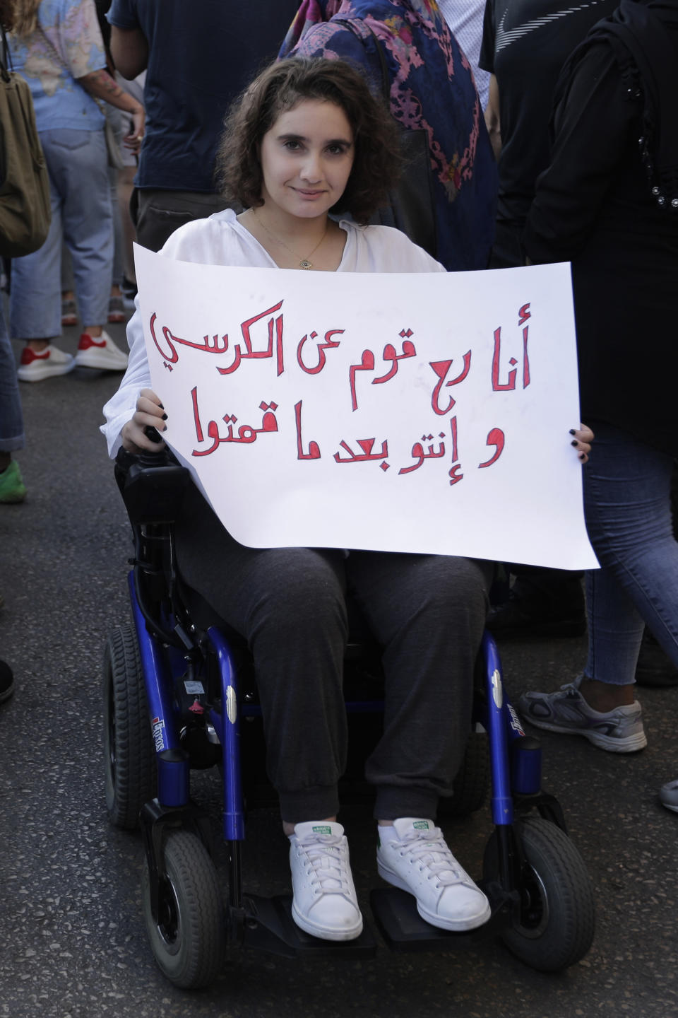 An anti-government protester in a wheelchair holds a banner that reads in Arabic "I will get out from my chair, before you do," during a protest in Beirut, Lebanon, Tuesday, Oct. 22, 2019. Prime Minister Saad Hariri briefed western and Arab ambassadors Tuesday of a reform plan approved by the Cabinet that Lebanon hopes would increase foreign investments to help its struggling economy amid wide skepticism by the public who continued in their protests for the sixth day. (AP Photo/Hassan Ammar)