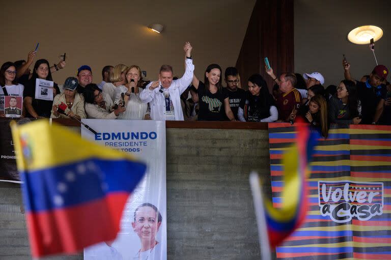 El candidato presidencial venezolano Edmundo González y la líder de la oposición venezolana María Corina Machado  saludan a los estudiantes durante un acto de campaña en la Universidad Central de Venezuela en Caracas el 14 de julio de 2024. 