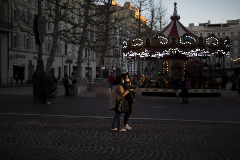 FILE - In this Jan. 14, 2021, file photo, people take a selfie together on a main street before a curfew is enforced to prevent the spread of the coronavirus in Marseille, southern France. While most of Europe kicked off 2021 with earlier curfews or stay-at-home orders, authorities in Spain insist the new coronavirus variant causing havoc elsewhere is not to blame for a sharp resurgence of cases and that the country can avoid a full lockdown even as its hospitals fill up. (AP Photo/Daniel Cole, File)