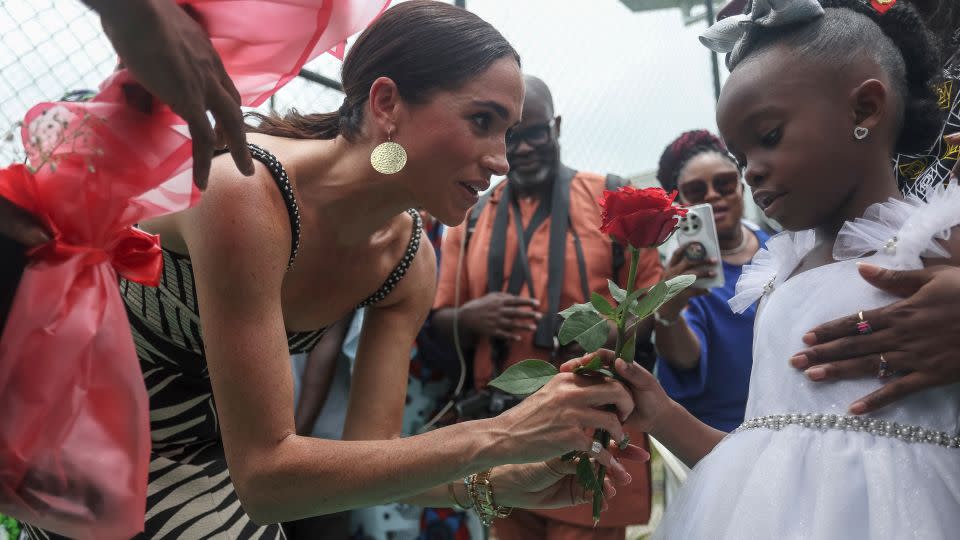 Meghan, Duchess of Sussex, receives flowers from a girl upon her arrival with Britain's Prince Harry, Duke of Sussex, for an exhibition sitting volleyball match at Nigeria Unconquered, a local charity organization that supports wounded, injured, or sick servicemembers, in Abuja on May 11, 2024. - Kola Sulaimon/AFP/Getty Images