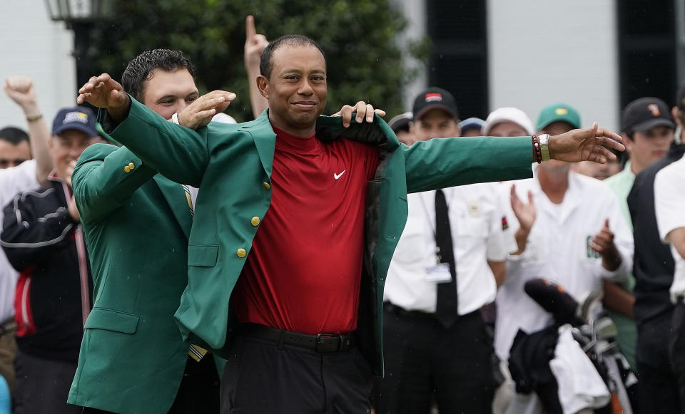 Patrick Reed helps Tiger Woods with his green jacket after Woods won the Masters golf tournament Sunday, April 14, 2019, in Augusta, Ga. (AP Photo/David J. Phillip)