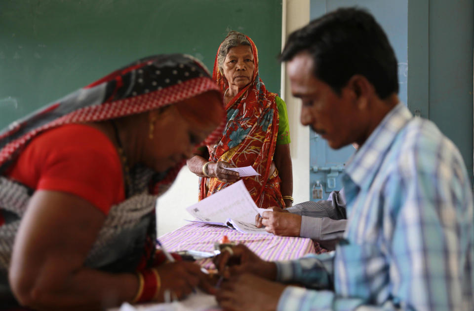 A polling officer checks the identity of a voter, as another awaits her turn at a polling station in Rajnandgaon, in the central Indian state of Chhattisgarh, now the center of India's four-decade Maoist insurgency, Thursday, April 17, 2014. Indians cast ballots Thursday on the biggest day of voting in the country's weekslong general election, streaming into polling stations even in areas where rebels threatened violence over the plight of India's marginalized and poor. The state of Chhattisgarh itself was formed only in 2000, carved from its western neighbor Madhya Pradesh based on its large tribal population. (AP Photo/Rafiq Maqbool)