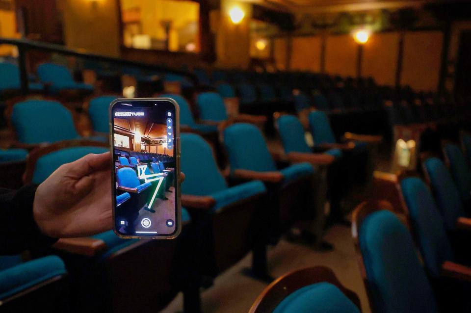 Motor City Ghost Hunters member Colleen Miller, 51, of Oxford, uses the Ghost Tube app on her iPhone, which detected a spirit in a seat near her, inside the Redford Theatre in Redford on Friday, Oct. 7, 2022.