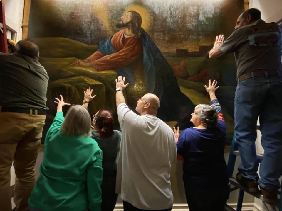 Congregants from Shrewsbury St. Paul’s and New Hope Fissell’s congregations support the heavy painting of Jesus in Gethsemane as the final fasteners are removed from the Shrewsbury church’s chancel wall.