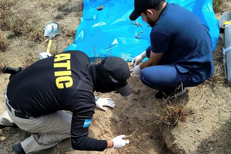 Photo publiée par l'Agence technique d'investigation criminelle du Honduras (ATIC) montrant des agents en train d'exhumer des restes enfouis dans des fosses clandestines, dans le quartier de Lomas del Carmen, au nord-est de San Pedro Sula, au Honduras, le 6 juin 2024 (Handout)