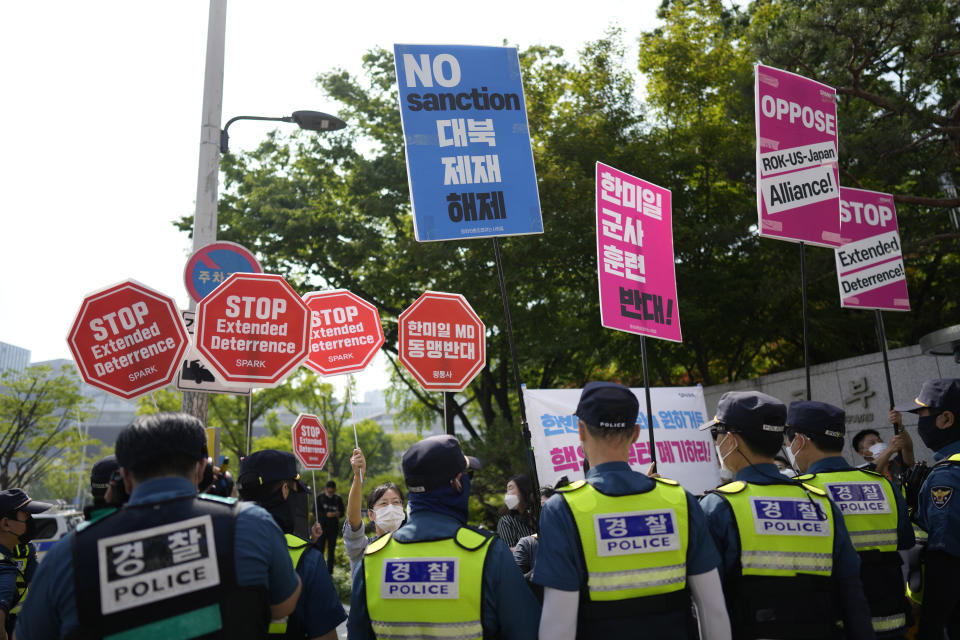 Protesters shout slogans as police officers stand guard during a rally outside of Foreign Ministry where a trilateral meeting among the United States, South Korea and Japan is held in Seoul, South Korea, Friday, June 3, 2022. (AP Photo/Lee Jin-man)