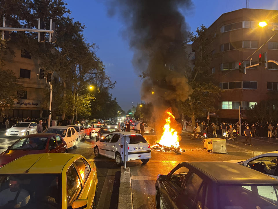 DOSSIER - En ce 19 septembre 2022, photo prise par un individu non employé par l'Associated Press et obtenue par l'AP hors d'Iran, une moto de police brûle lors d'une manifestation contre la mort d'une jeune femme qui avait été arrêtée pour avoir enfreint le code vestimentaire conservateur du pays, au centre-ville de Téhéran, en Iran.  (AP Photo, Fichier)