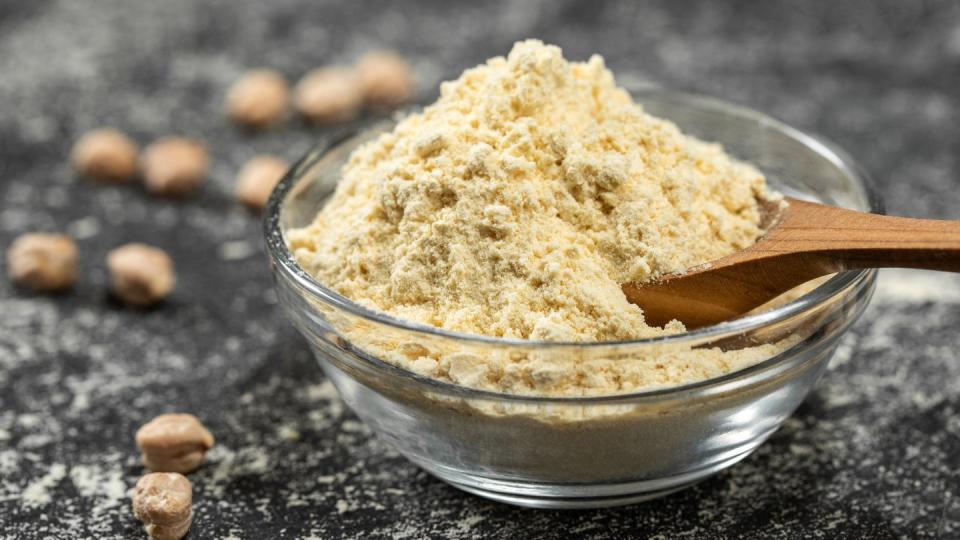 chickpea flour in a glass bowl, on a black background, close up legumes organic food selective focus front view