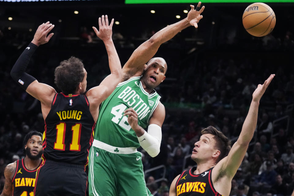 Boston Celtics center Al Horford (42) passes the ball while pressured by Atlanta Hawks guard Trae Young (11) during the first half of an NBA basketball game Wednesday, Feb. 7, 2024, in Boston. (AP Photo/Charles Krupa)