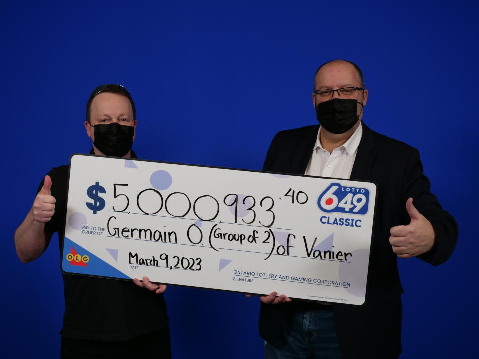 German Ouellette and Marc Lafleur hold a check for $5,000,933.40 from OLG.