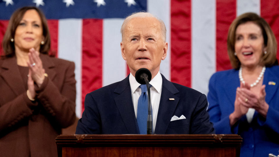 President Biden looks skyward, while Vice President Kamala Harris and Speaker of the House Nancy Pelosi applaud.