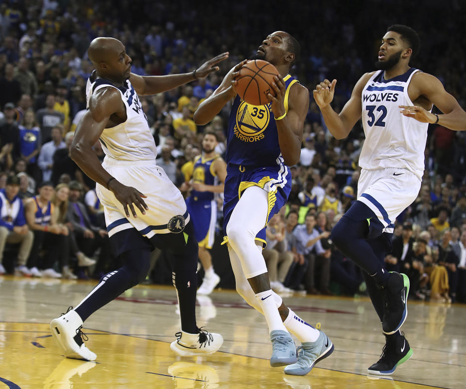 Golden State Warriors' Kevin Durant (35) looks to shoot between Minnesota Timberwolves' Anthony Tolliver, left, and Karl-Anthony Towns (32) during the second half of an NBA basketball game Friday, Nov. 2, 2018, in Oakland, Calif. (AP Photo/Ben Margot)
