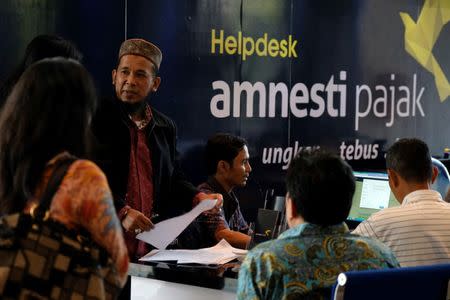 People wait at a help desk for tax amnesty at the country's tax headquarters in Jakarta, Indonesia September 30, 2016. REUTERS/Beawiharta