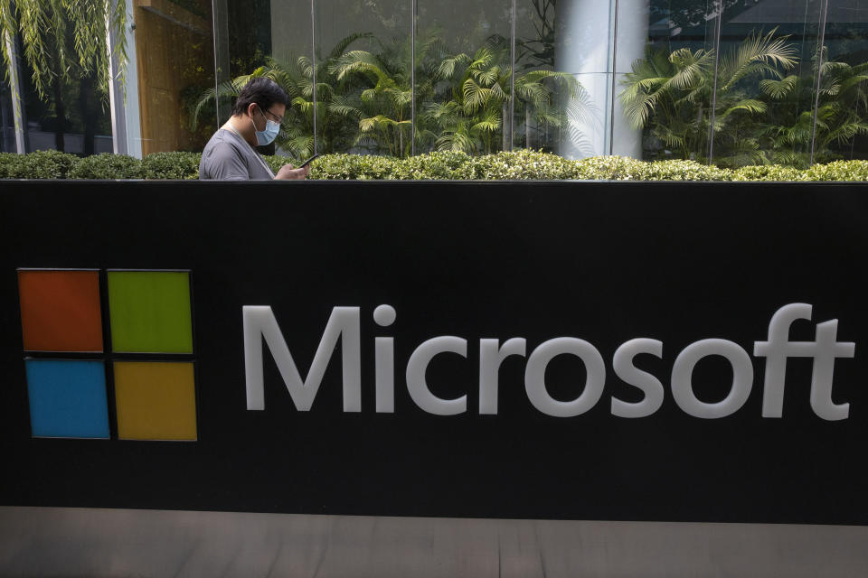 A man wearing a mask looks at this phone outside the Microsoft office in Beijing, China on Friday, Aug. 7, 2020. U.S. President Donald Trump on Thursday ordered a sweeping but unspecified ban on dealings with the Chinese owners of consumer apps TikTok and WeChat, although it remains unclear if he has the legal authority to actually ban the apps from the U.S. Earlier in the week, Trump threatened a deadline of Sept. 15 to "close down" TikTok unless Microsoft or another company acquires it, a threat the new executive order appears to formalize. (AP Photo/Ng Han Guan)