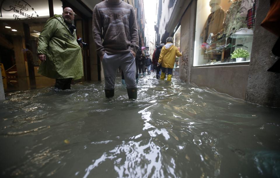 People wade through water on the occasion of a high tide, in a flooded Venice, Italy, Tuesday, Nov. 12, 2019. (Photo: Luca Bruno/AP)