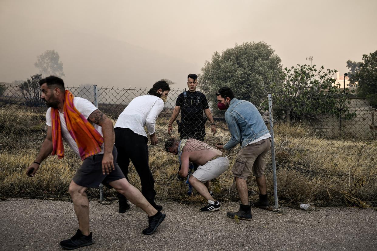 Local residents try to protect a house from the raging fire in Lagonisi area, some 35 kilometeres from Athens (AFP via Getty Images)