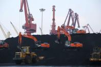 Workers operate loaders unloading imported coal at a port in Lianyungang, Jiangsu