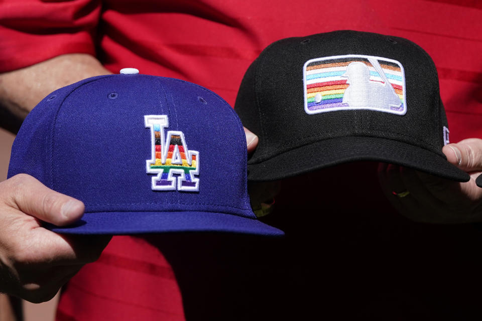 FILE - Pride-themed hats for the Los Angeles Dodgers and Major League Baseball are displayed by sports officials on Pride Day at Oracle Park before a baseball game between the Giants and the Dodgers in San Francisco, Saturday, June 11, 2022. Under a barrage of criticism from some conservative Catholics, the team rescinded an invitation to a satirical LGBTQ+ group called the Sisters of Perpetual Indulgence to be honored at the 2023 Pride Night. A week later, after a vehement backlash from LGBTQ+ groups and their allies, the Dodgers reversed course — re-inviting the Sisters’ Los Angeles chapter to be honored for its charity work and apologizing to the LGBTQ+ community. (AP Photo/Jeff Chiu, File)