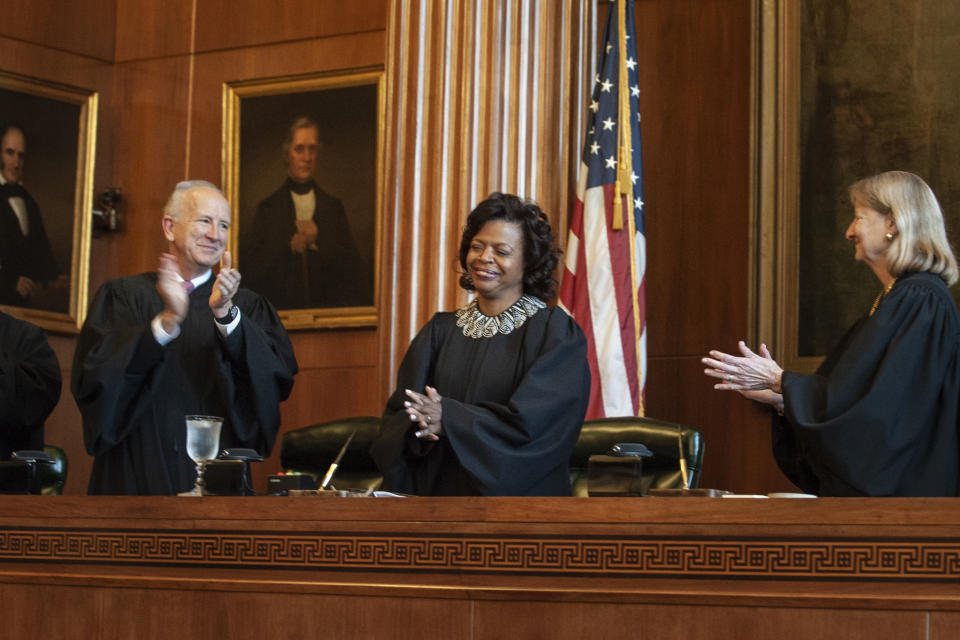 FILE - In this March 7, 2019 file photo, Associate Justices Paul Newby and Robin Hudson applaud for new Chief Justice Cheri Beasley, center, of the N.C. Supreme Court during Beasley's investiture ceremony in Raleigh. In North Carolina's Supreme Court chamber, above the seat held by Beasley, the second African American chief justice, hangs a towering painting of Chief Justice Thomas Ruffin, a 19th century slave owner and jurist who authored a notorious opinion about the “absolute” rights of slaveholders over the enslaved. In October 2018 the state Supreme Court named a commission to review the portraits in the building that houses the court ,including Ruffin's. (Paul Woolverton/The Fayetteville Observer via AP)