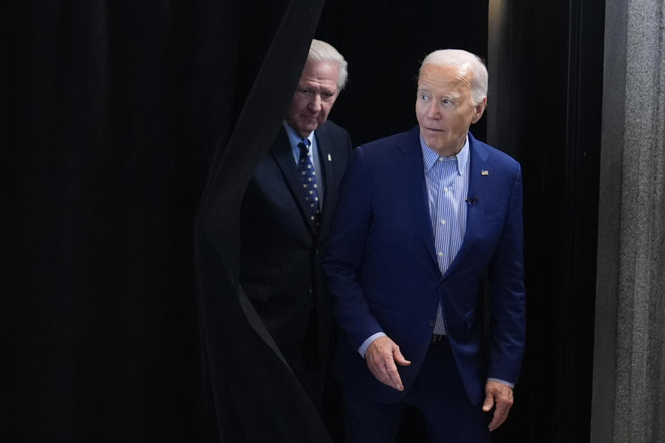 President Joe Biden, right, and United Steelworkers Union International President, David McCall, step out from behind a curtain to greet steelworkers at the United Steelworkers Headquarters, in Pittsburgh, Pa., April 17, 2024. (AP Photo/Alex Brandon)